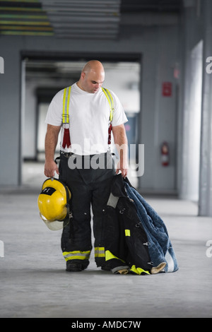 A fire fighter holding a jacket and a hardhat. Stock Photo