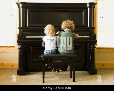 Rear view of two children sitting at upright piano