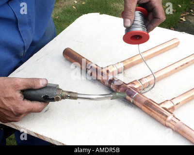 Close up of plumber using a propane gas torch to heat solder to make a