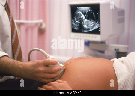 Male doctor using probe during ultrasound test with fetus on screen Stock Photo