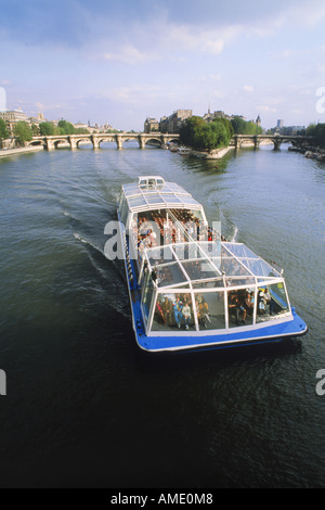 Passenger boat touring Paris on River Seine with Pont Neuf and Île de la Cite beyond Stock Photo