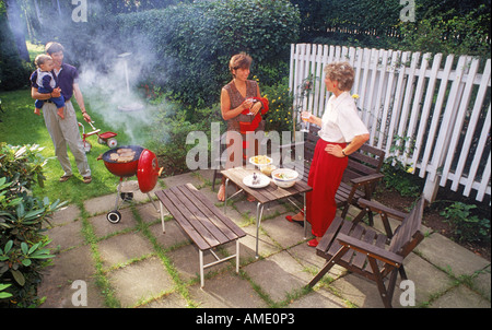 Family barbecue in backyard around steaks and smoke Stock Photo