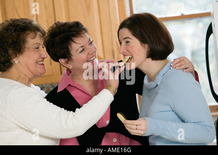 Two mature women feeding a young woman. Stock Photo