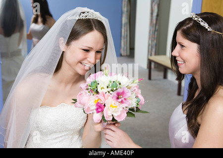 Bride with her bridesmaid holding flowers. Stock Photo