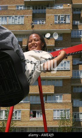 A 10 year old boy playing on a swing in front of a housing estate, Forest Hill, London, UK. 2006. Stock Photo