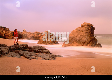 Woman Standing on Rocks on Beach Stock Photo