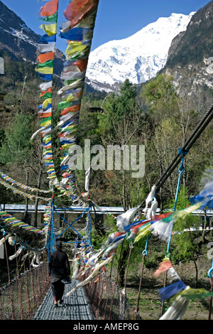 Woman crossing a bridge over Marsyangdi river. Chame village. Annapurna circuit trek. Nepal Stock Photo