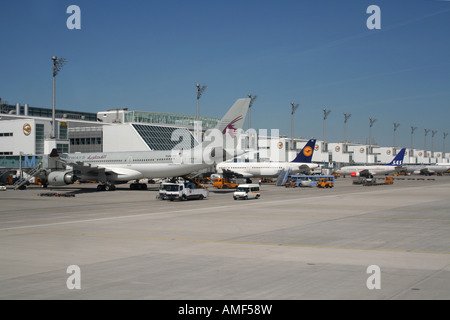 Airport and planes. Aircraft at their gates at Munich Airport, Germany. A Qatar Airways Airbus A330 is in the foreground. Air travel. Stock Photo