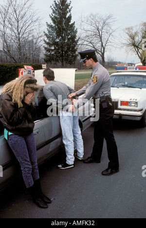 High school teenagers arrested by police for drinking alcohol while driving a car Stock Photo