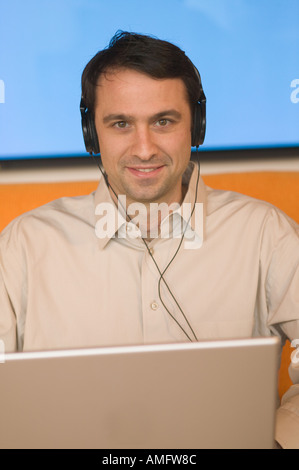 Man using a laptop with plasma screen in background Stock Photo