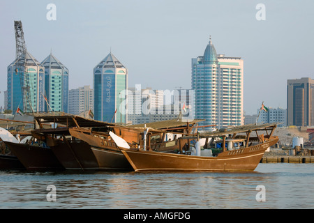 Hi-rise tower buildings, Al Sharjah, Arab wooden dhows, traditional sailing vessels. Boats in the creek, Umm al-Quwain, UAE United Arab Emirates Stock Photo