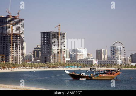 Residential buildings property units in Al Sharjah; Arab dhow  traditional sailing vessels moored in the creek, UAE United Arab Emirates Stock Photo