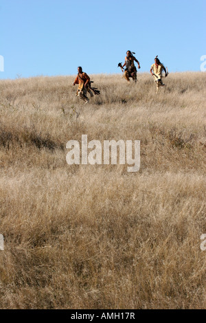 Three Native American Indian men crouching in the dead grasses hunting ...