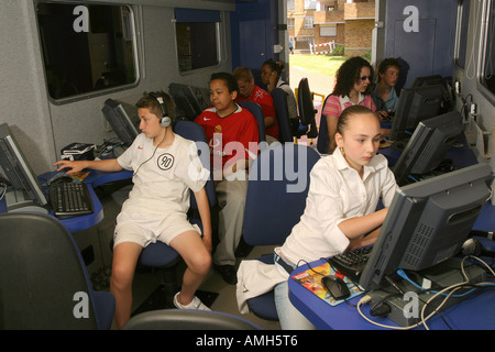 Young children using personal computers and the internet in a portable computer and internet resource cabin. Stock Photo