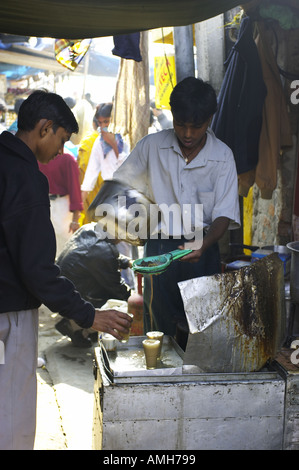 A young chai wallah pours our some hot chai, or tea, for a customer in INA market, New Delhi, India Stock Photo