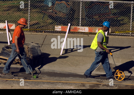 Construction workers measure distance using wheeled measuring devices Stock Photo