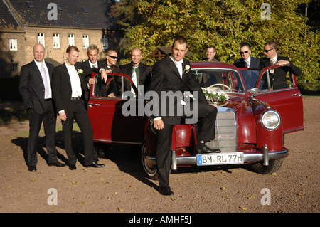 Groom sitting in old Mercedes wich is pushed by his friends Stock Photo