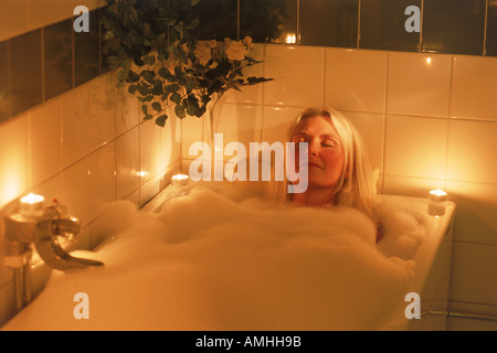 Candle lit bubble bath for relaxed blond woman Stock Photo