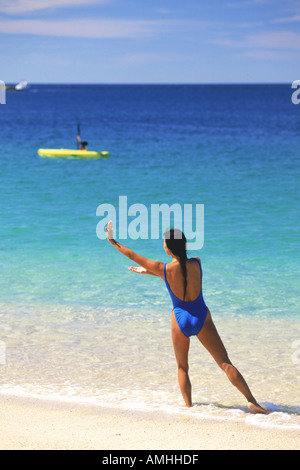 Woman doing yoga and Tai Chi exercises alone on sandy shore Stock Photo