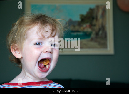 Three year old boy shows off a mouth full of food. Dorest, England Stock Photo