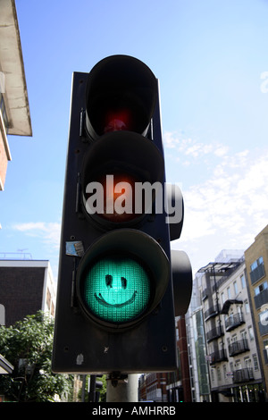 Traffic light on green with smiley face drawn on it. Old Street, Hackney,  London, England Stock Photo
