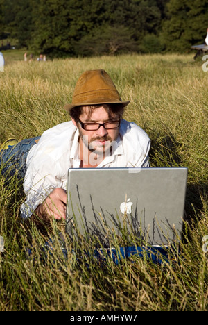 Man using an Apple laptop outdoors on Hampstead Heath, London, UK Stock Photo
