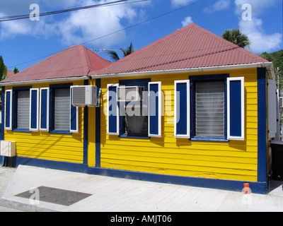Bright yellow wooden house with red tin roof blue shutters air conditioning and modern louvre windows Gustavia St Barts Stock Photo