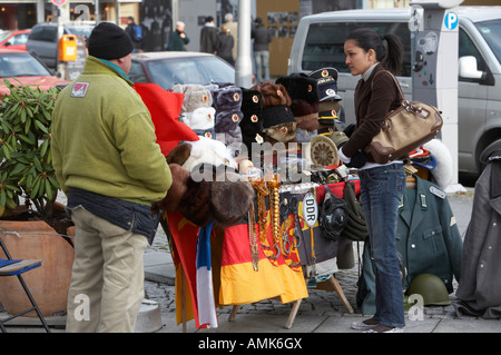 female tourist examines east german and russian memorabilia on sale at a street stall near checkpoint charlie Berlin Germany Stock Photo