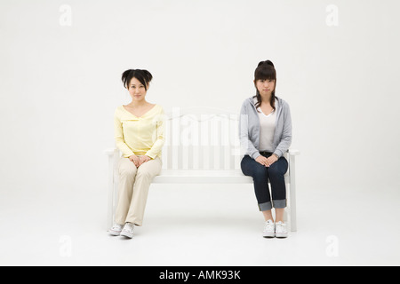 Two young women sitting on bench Stock Photo