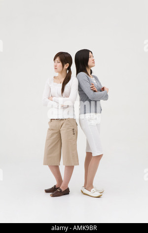 Two young women standing back to back, white background Stock Photo - Alamy