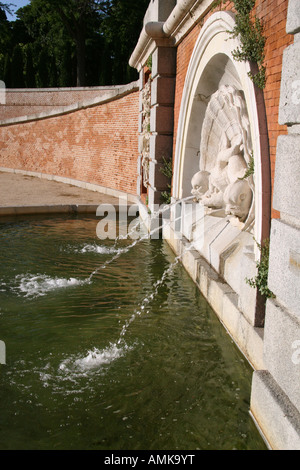 A wall fountain with jets of water and sculpted dolphin heads in Jardines del Buen Retiro Madrid Spain Stock Photo