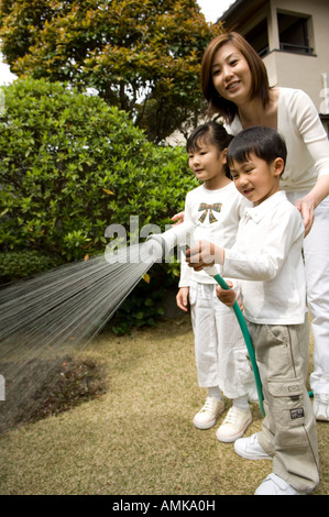 Mother and children watering trees Stock Photo