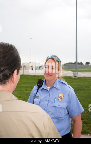 Female Correctional Officer talking to male inmate in the yard of maximum security prison. Stock Photo