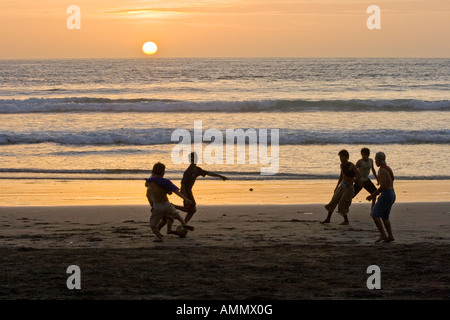 Indonesian Boys Playing Football at Sunset on Kuta Beach Bali Indonesia Stock Photo