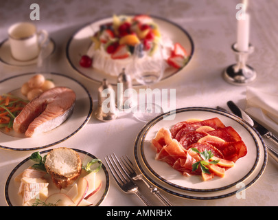 Complete meal of starter Charcutterie, Main Course, Salmon Steak, Dessert Pavlova. Dinner or a dining setting on a table. Stock Photo
