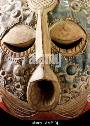 Ethnic traditional African mask used for tribal dances and events. Carved from wood with beaten metal overlay. Art and craft. Stock Photo