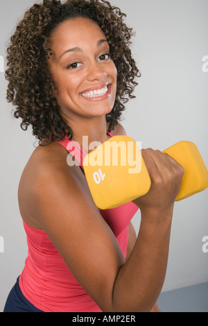 Delighted African American athletic female with strong arms showing biceps  and looking away stock photo - OFFSET