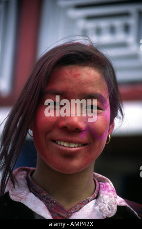 A young Nepali girl, her face covered in Gulal (red dye) for the Holi festival (festival of colours), in the Nepali Himalaya, Nepal Stock Photo