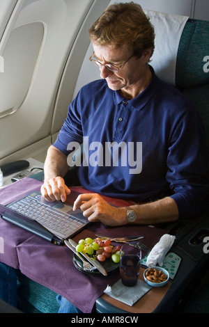 Middle Aged Caucasian Man using a Laptop Sitting Business Class on an Airplane Stock Photo