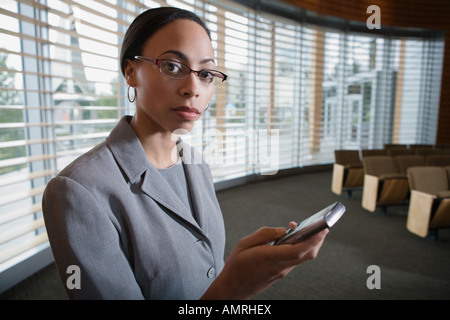 African businesswoman holding cell phone Stock Photo