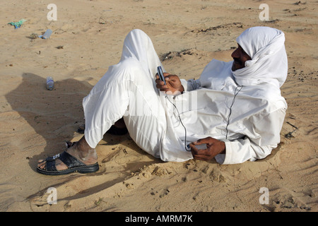 Man in the desert, using his mobile phone, Dubai, United Arab Emirates Stock Photo