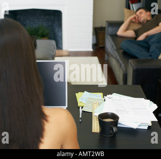 Woman Working at Computer and Man Napping on Couch