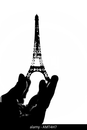 Silhouetted Eiffel Tower model with hand cupping the base Stock Photo