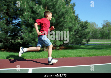 DM 8 year old boy running wearing old tennis shoes Stock Photo