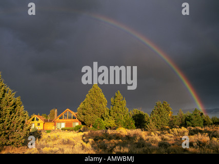 USA OREGON A rainbow brightens a dark stormy sky after a summer rain storm on the high desert near Bend Oregon Stock Photo
