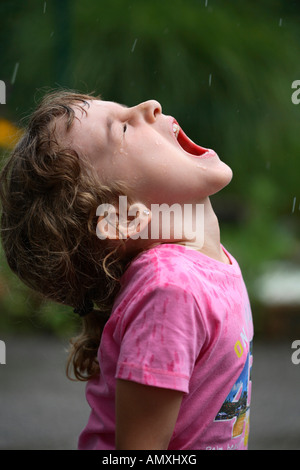 Close-up of girl standing with open mouth in rain Stock Photo