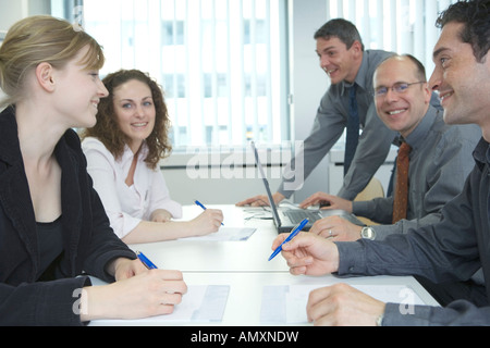 Side profile of businessmen and businesswomen smiling in meeting Stock Photo