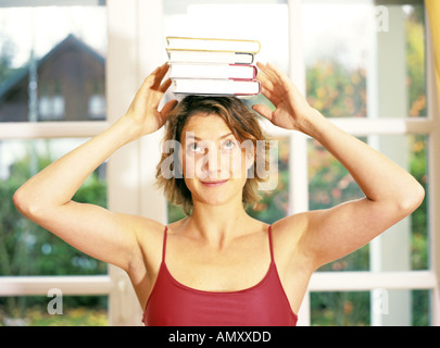 Young woman balancing books on head Stock Photo