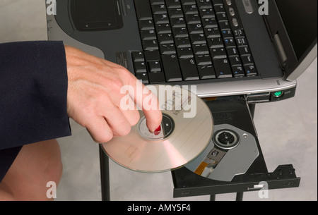 Caucasian woman’s hand inserting a CD into laptop computer, USA Stock Photo