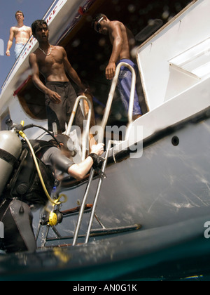 Maldives Scuba diver climbing ladder back onto boat after dive Stock Photo